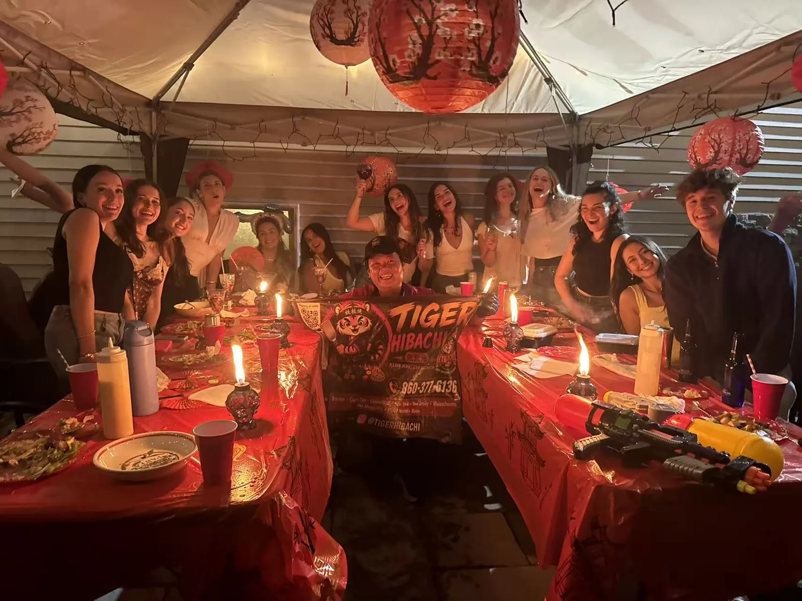 Night-time hibachi party under a tent with red lanterns and a large group of guests in Connecticut