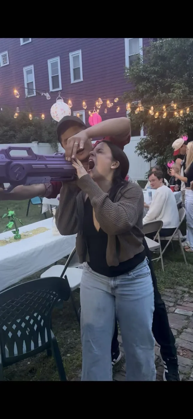 Guest taking a sake shot from the chef's sake gun under string lights at a Connecticut backyard hibachi party